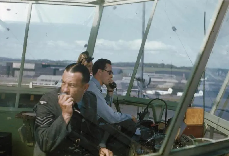 RAF controllers at the desk in the Prestwick tower cab with an American visitor, 1944